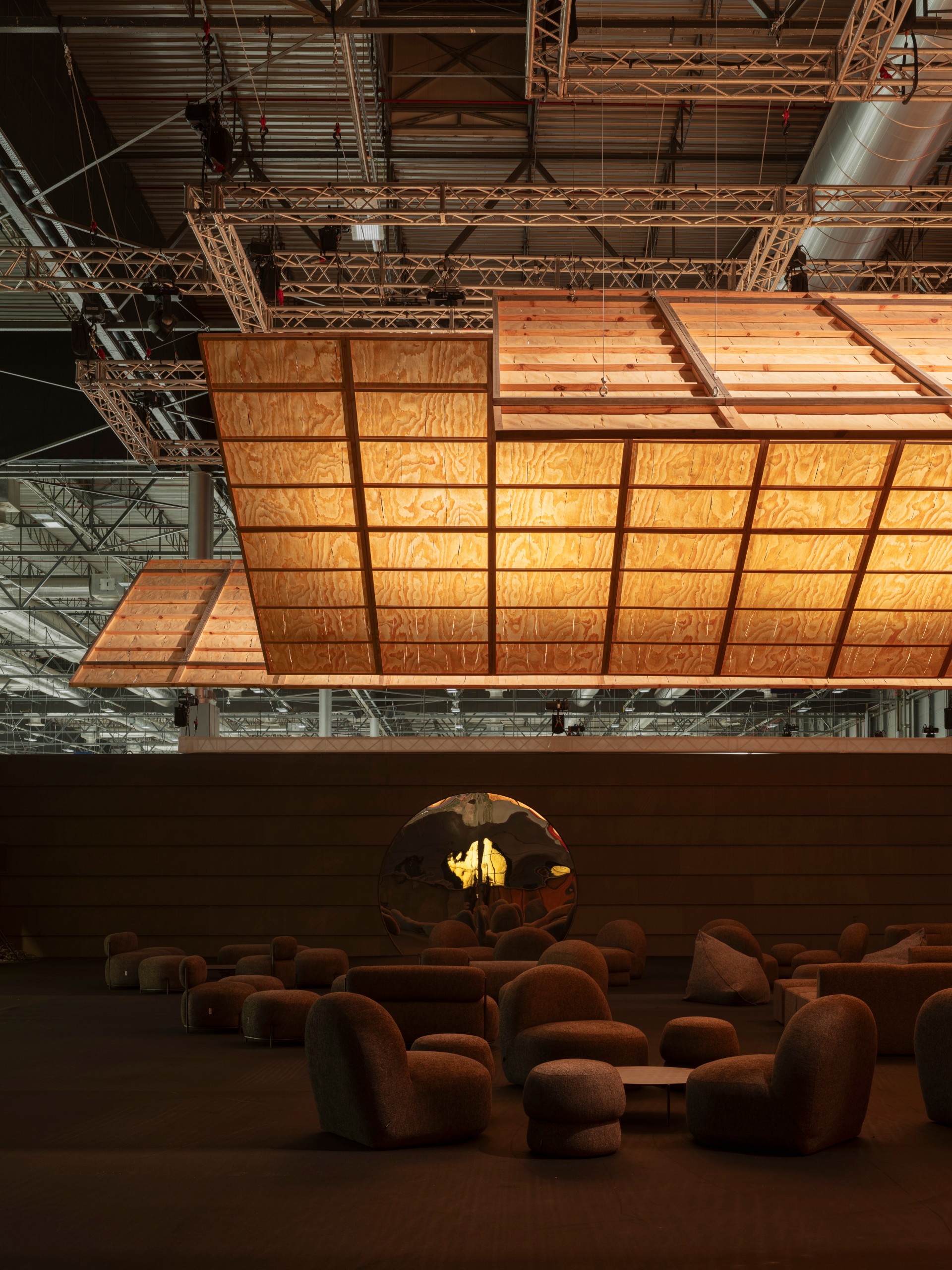 Upholstered seating beneath warm light with a round window in the back wall