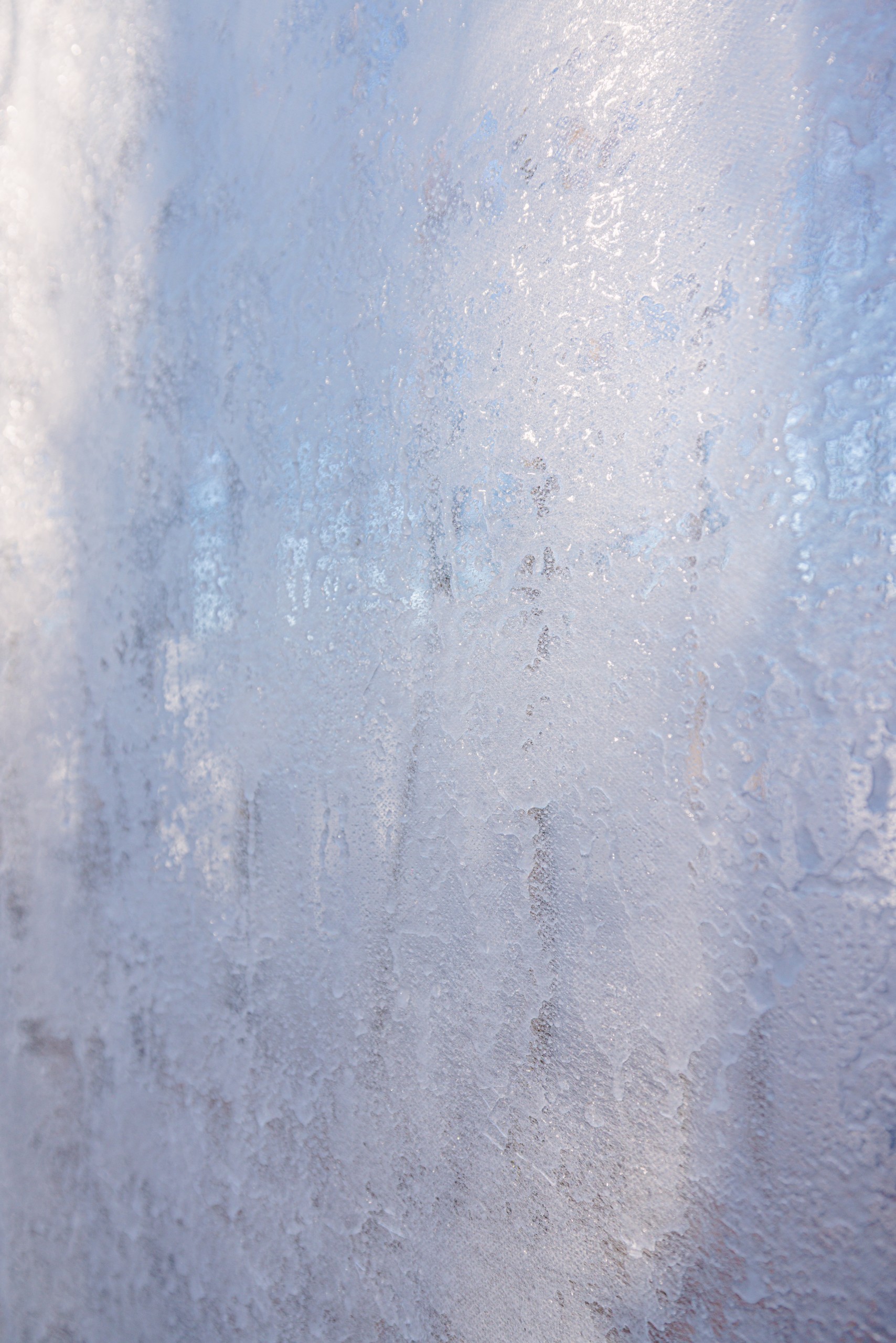 Close view of a frosted ice surface with pale blue light behind it