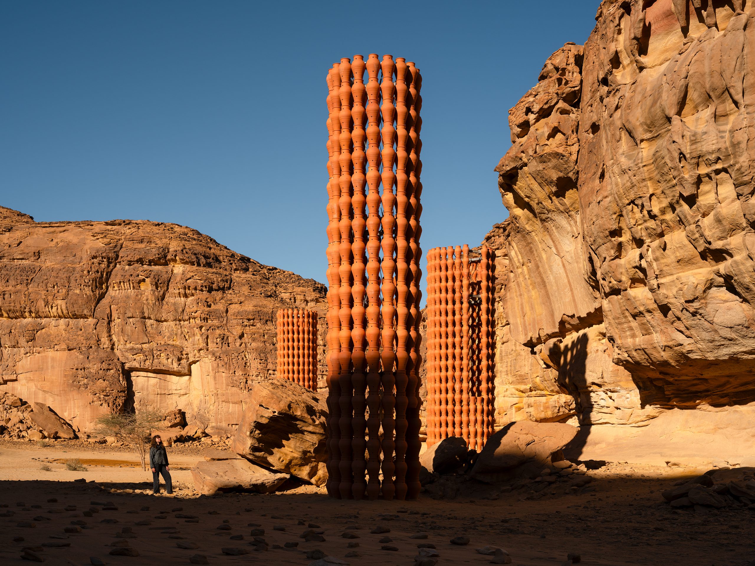 The porous tower lets the surrounding light and landscape pass through its handmade pattern.