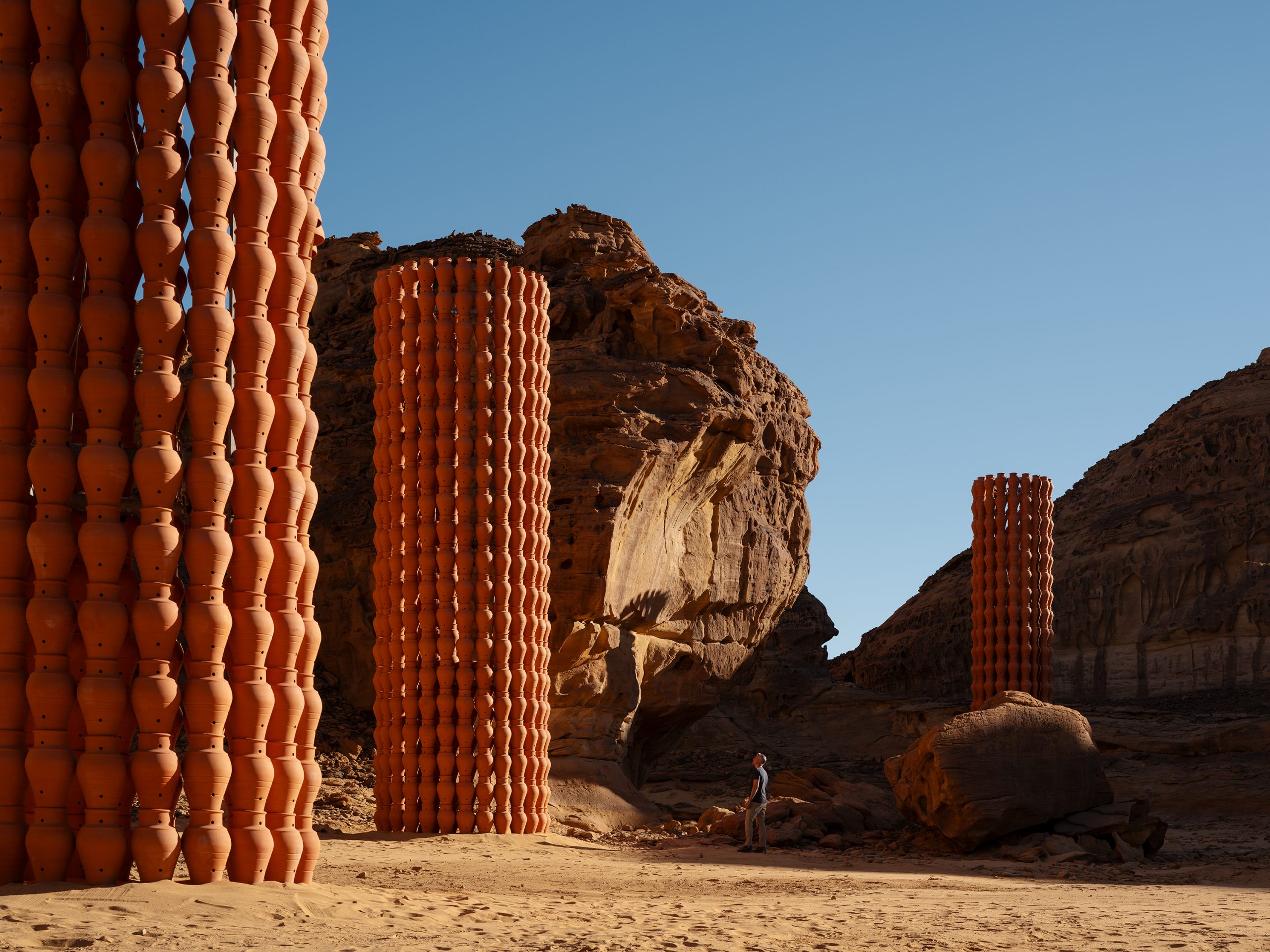 The installation’s earthen texture sits in contrast with the broad, bare terrain.