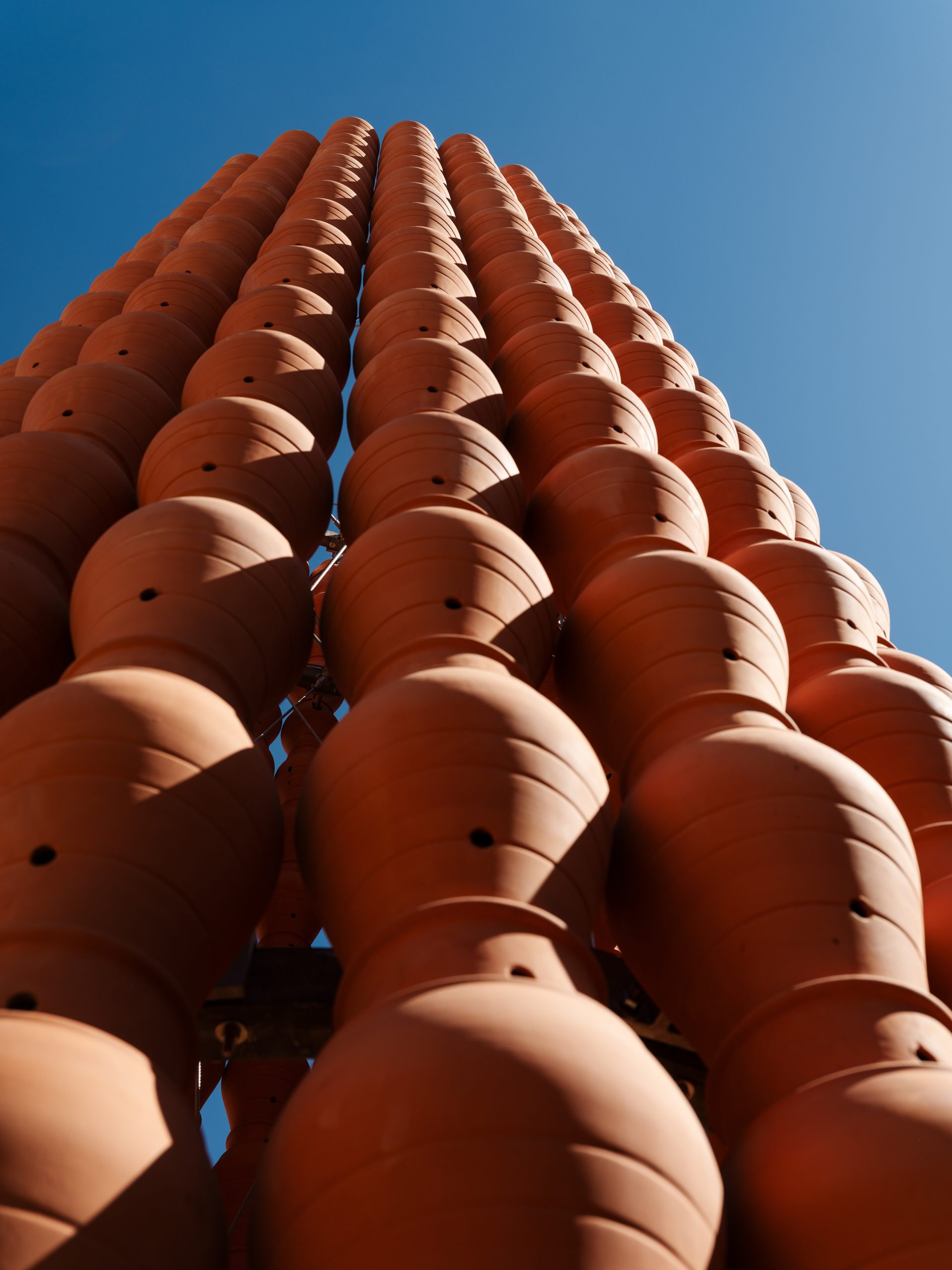 The repeated openings turn each jar into part of a larger porous surface.