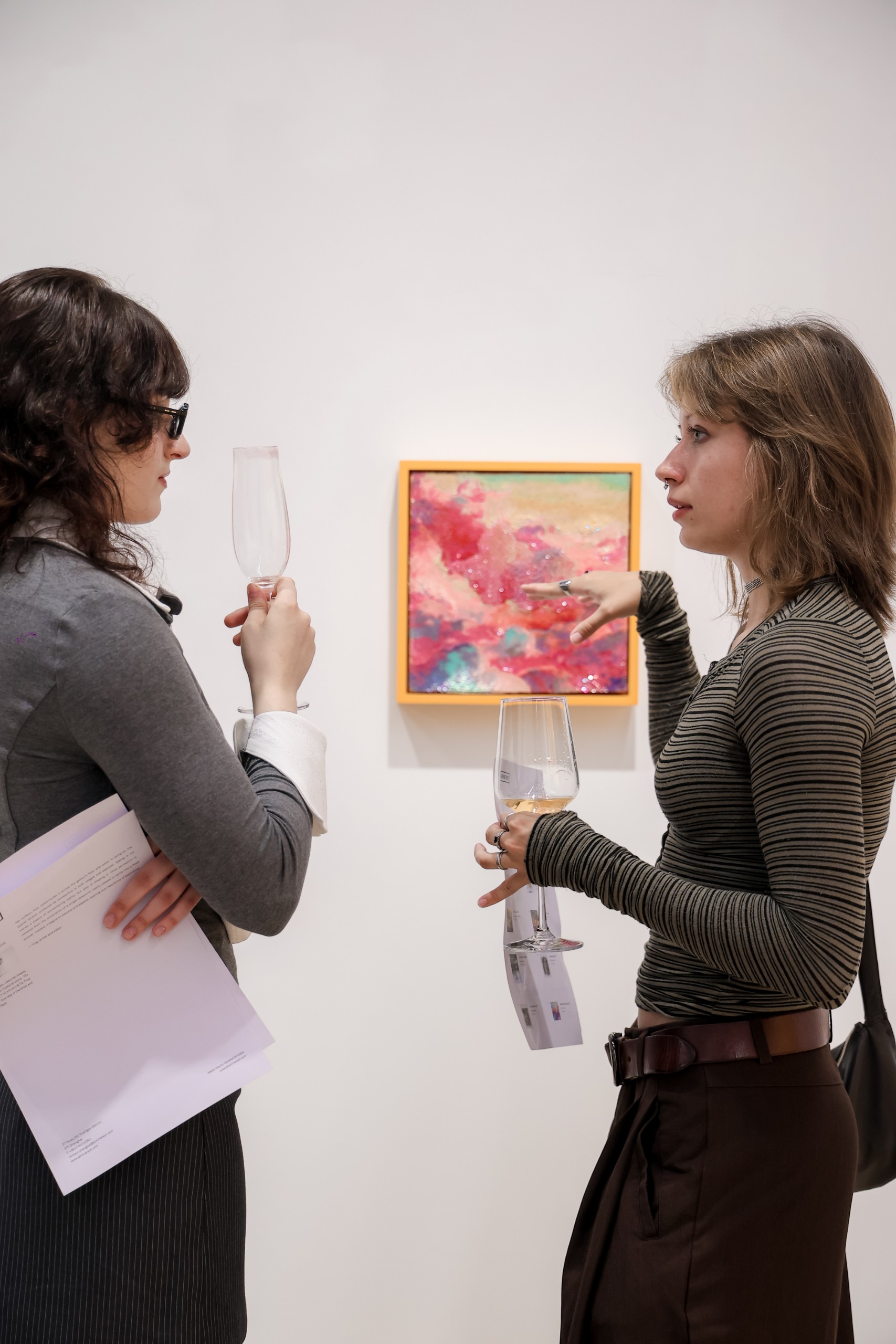 Two visitors talk beside a small cloud painting
