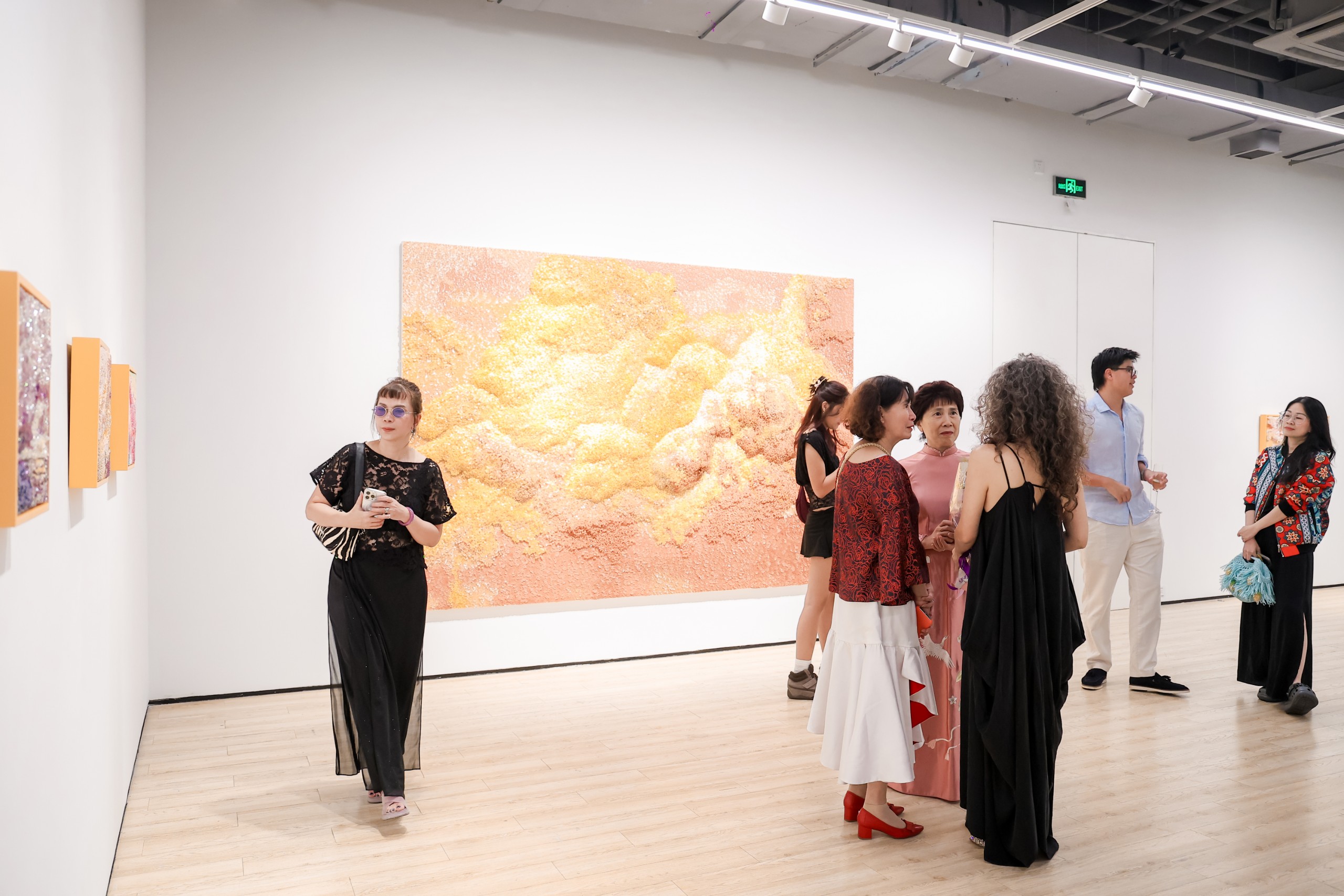 Visitors in front of a large golden beaded cloud work