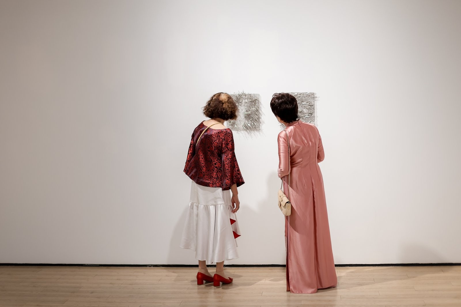 Two visitors looking at small works on the wall