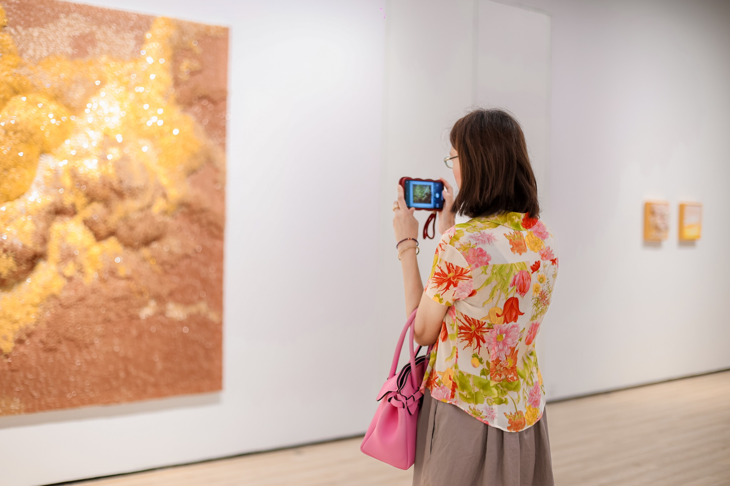 A visitor photographs the golden beaded surface of Fairer than a Fairy