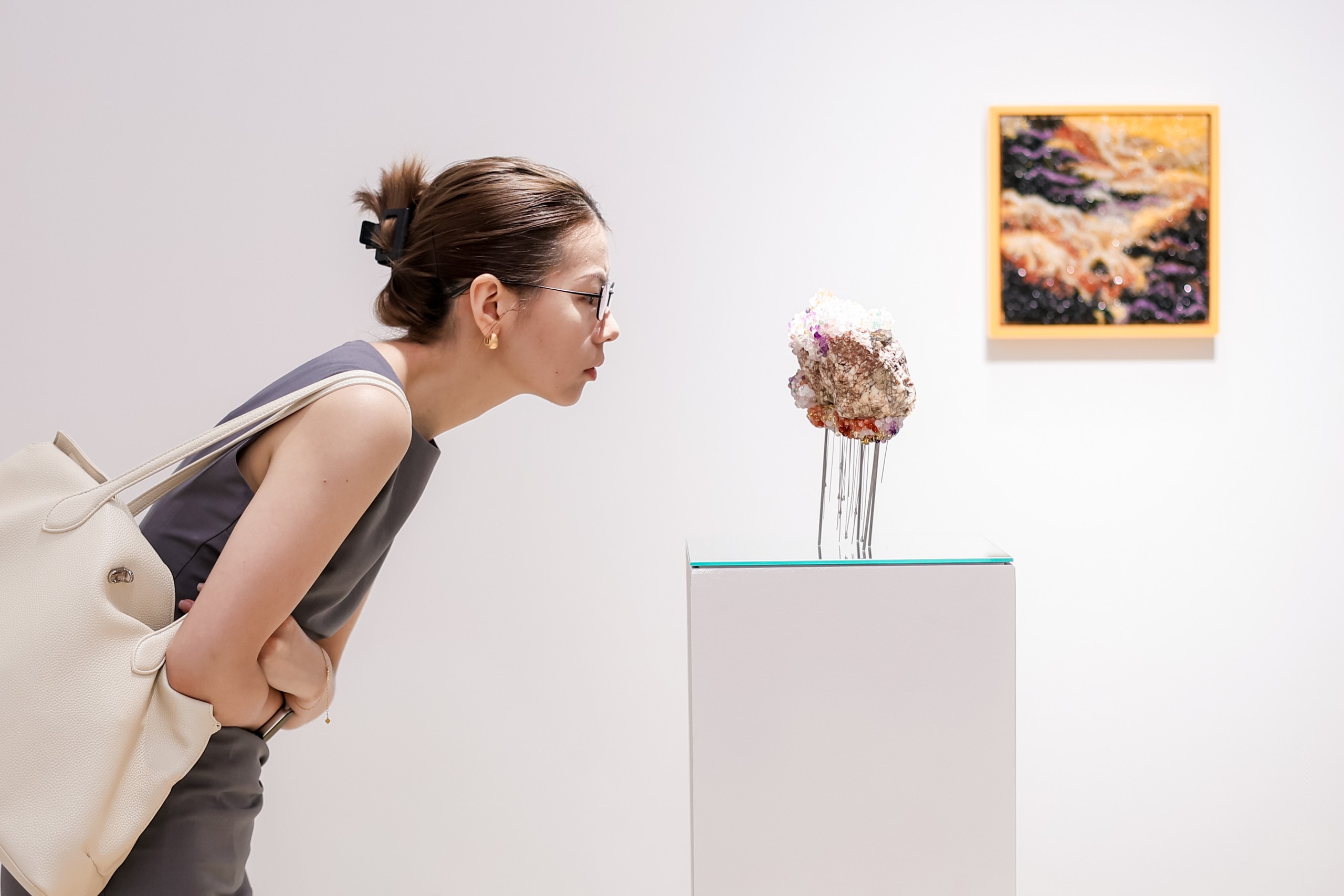 A visitor leans in to look at a small sculpture on a plinth