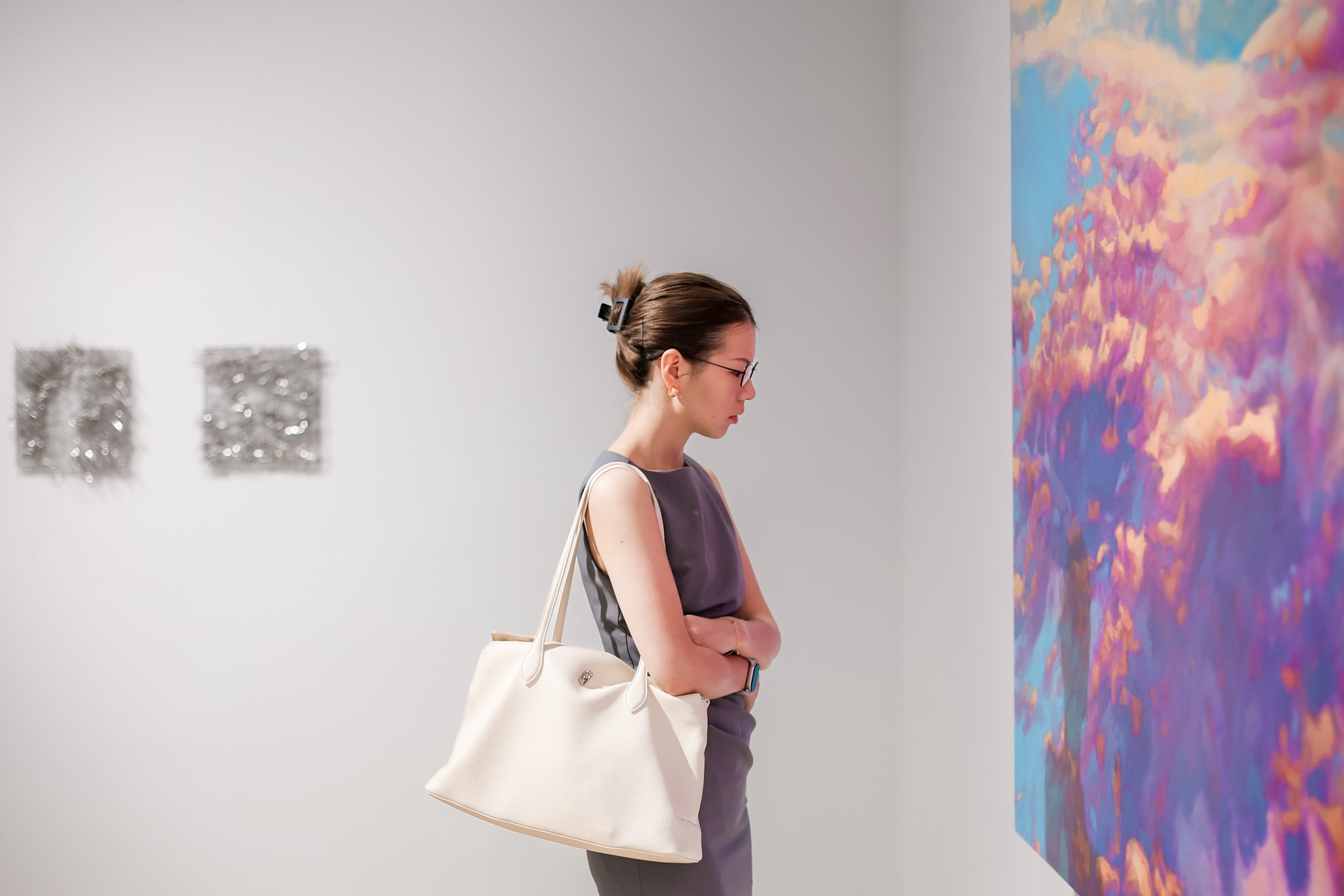 A visitor beside a pink and violet cloud painting