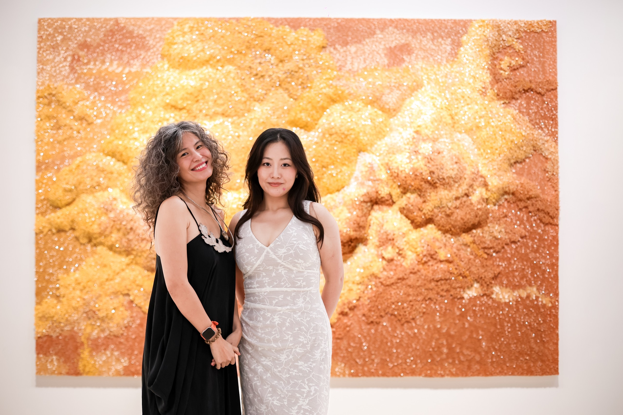 Two women in front of the golden beaded cloud work