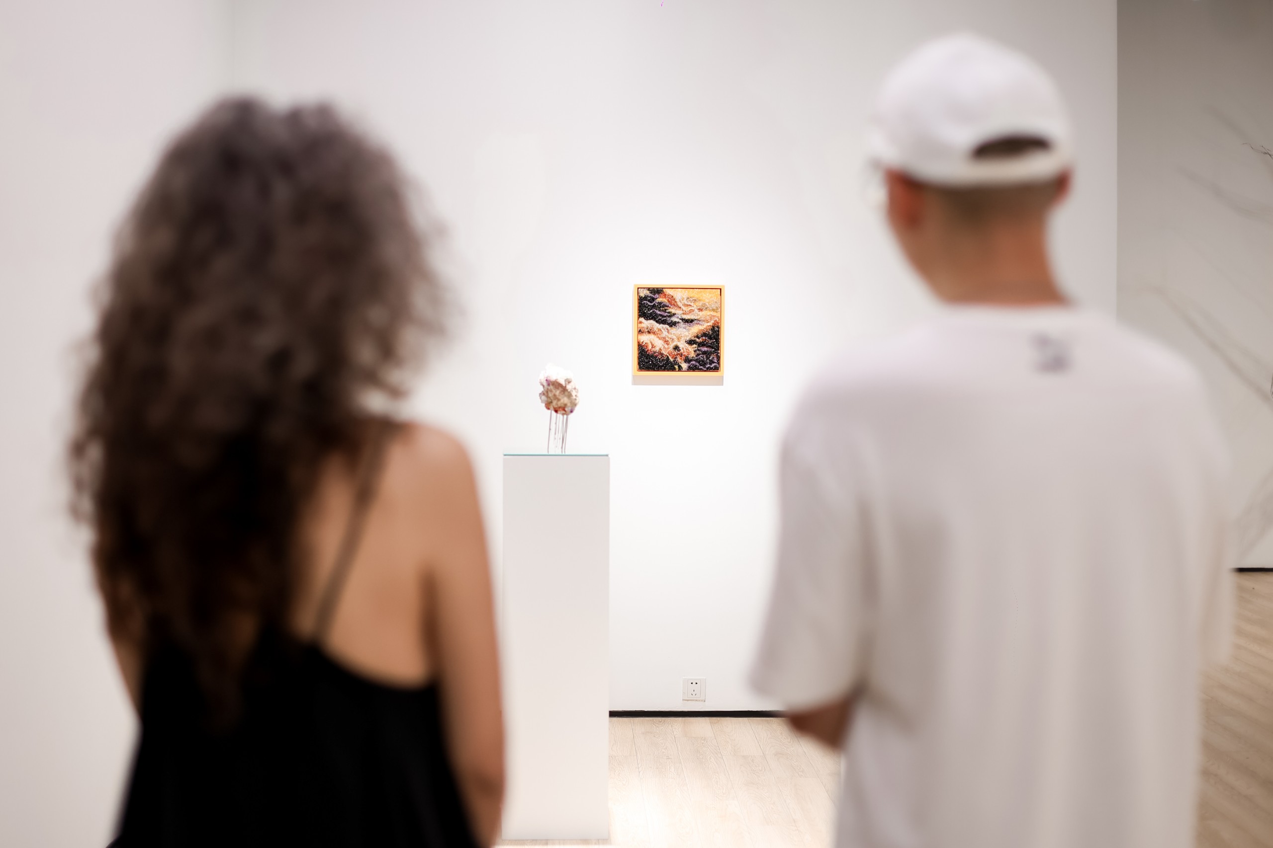 Visitors looking at a small painting and a sculpture