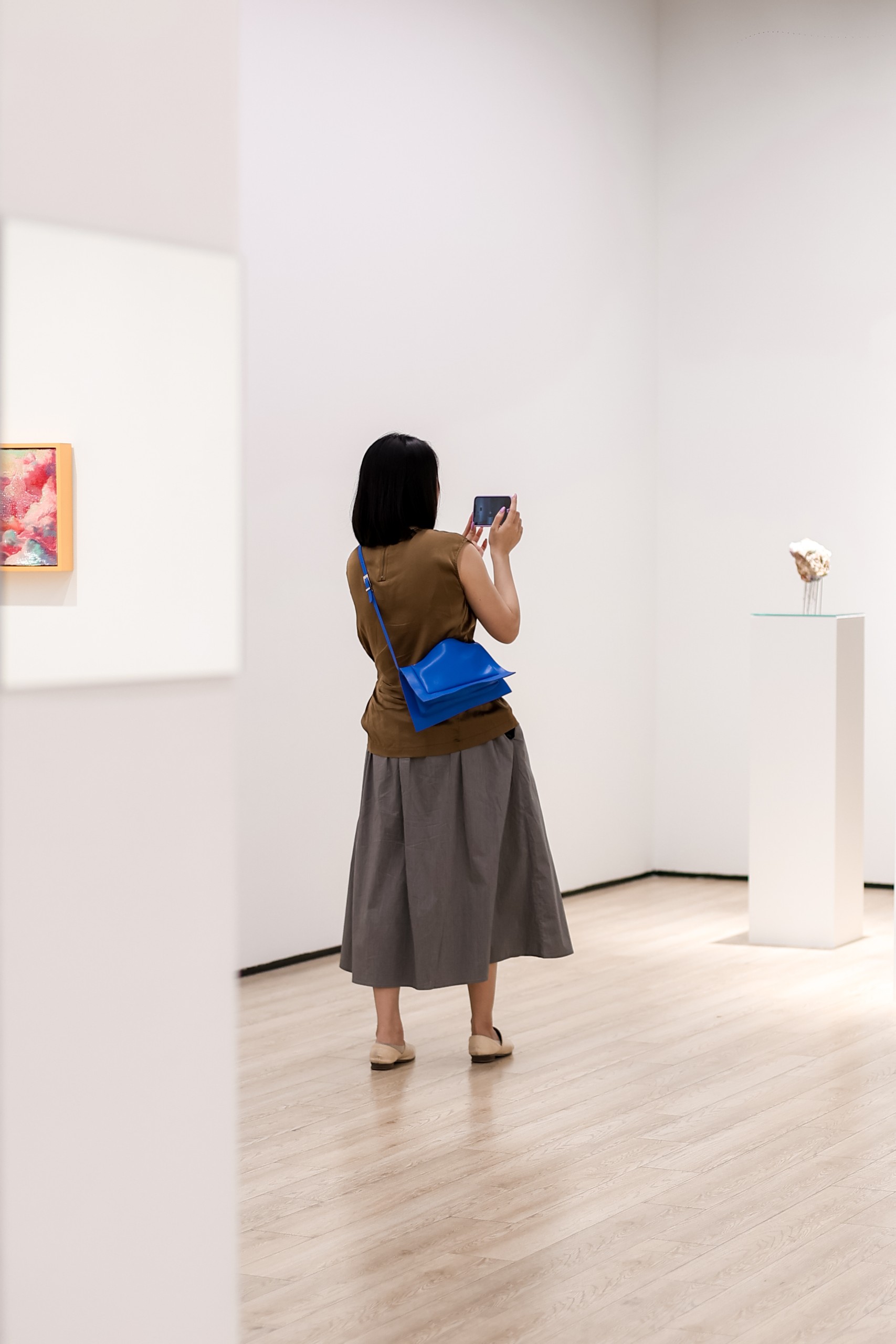 A visitor photographs works in the gallery