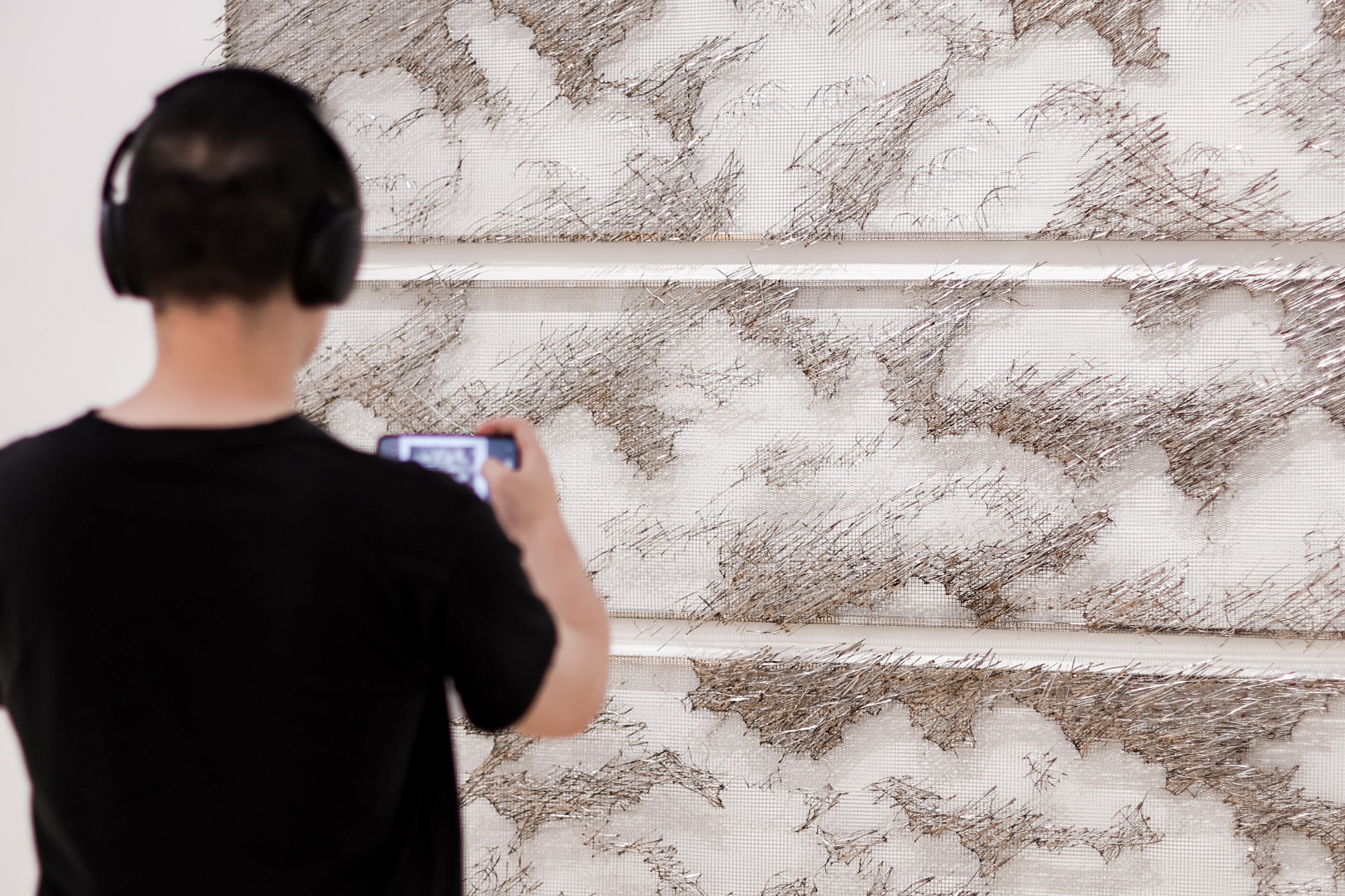 A visitor photographs the woven steel cloud panels