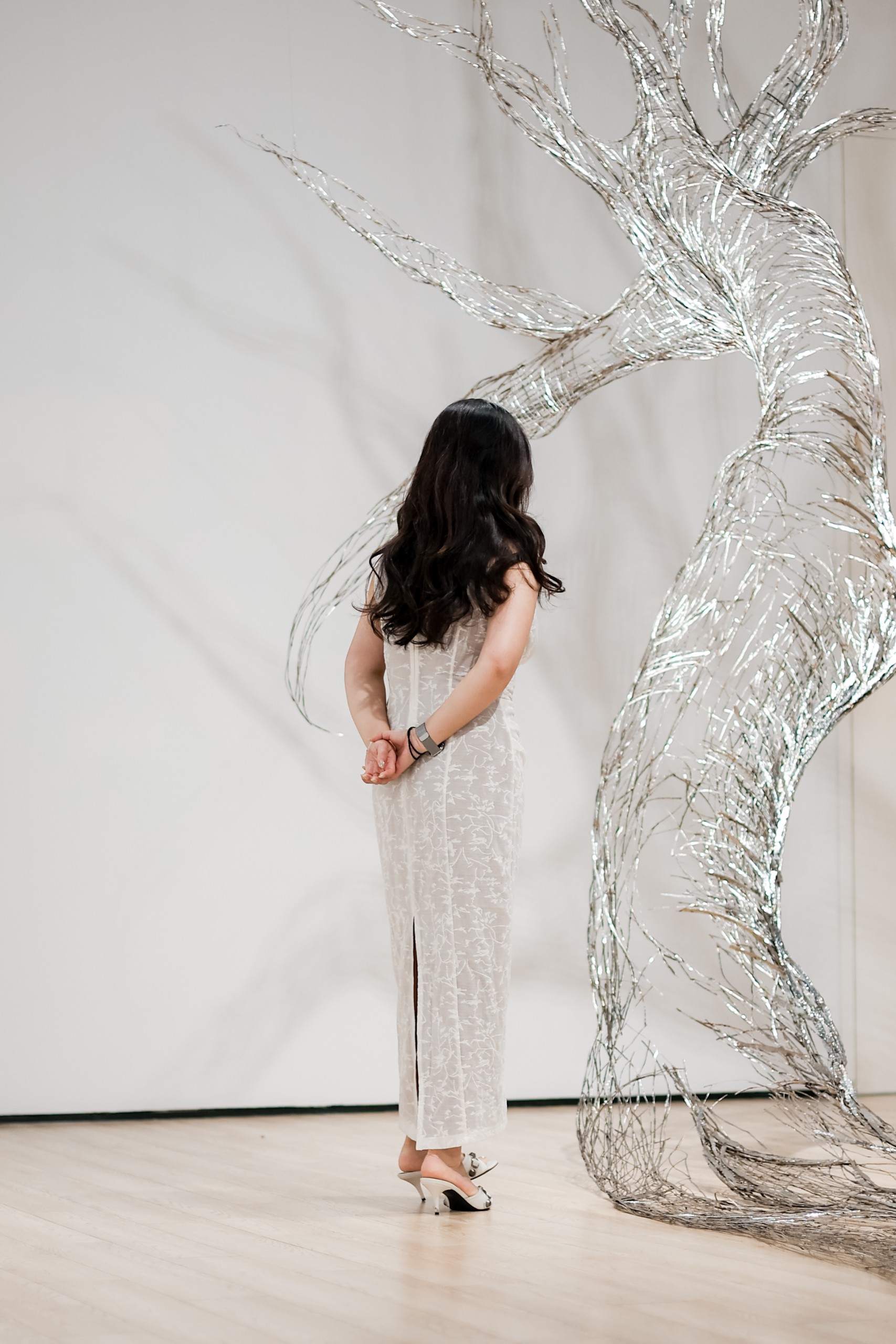 A visitor looks up at the steel tree rising along the wall