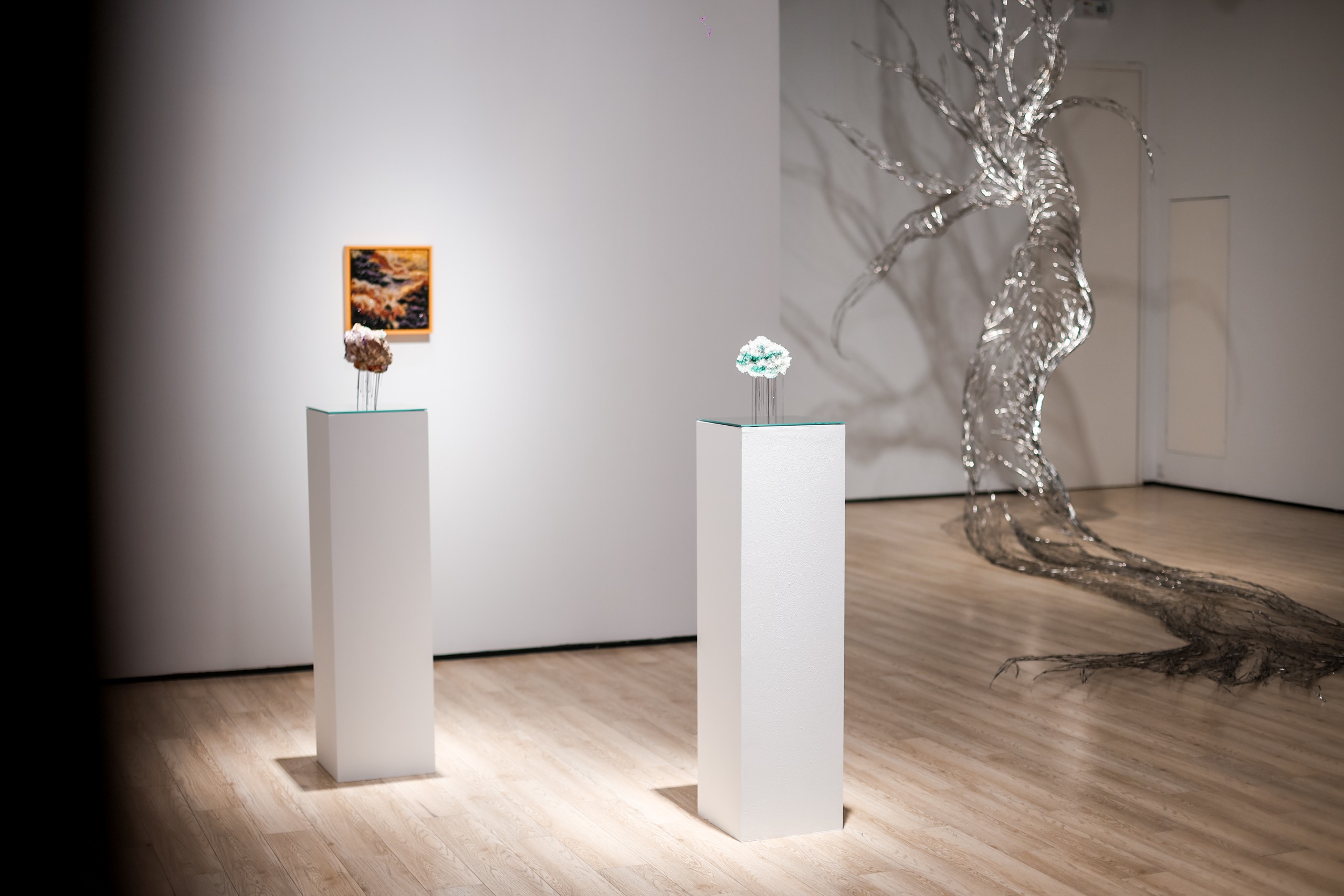 Sculptures on plinths with the steel tree in the background