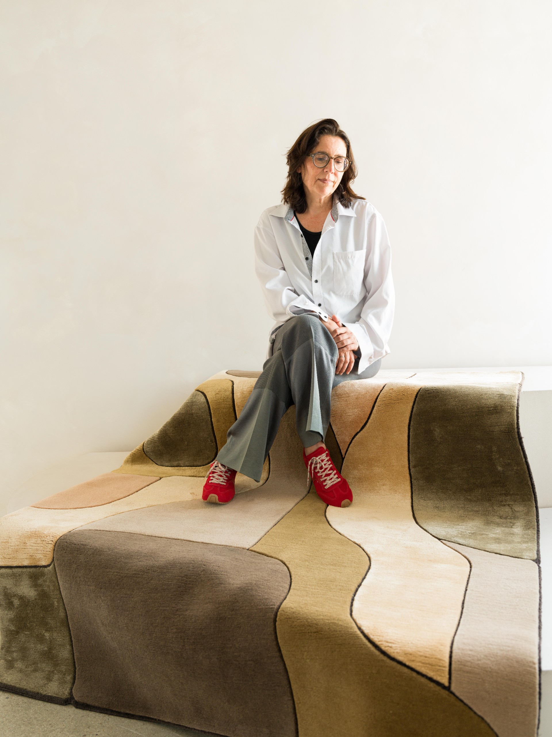 Woman seated on a draped earth-tone rug