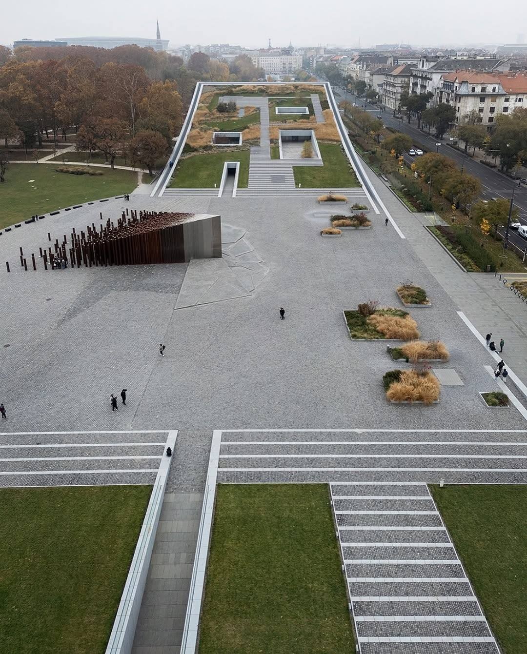 Visitors walk among the steel columns, experiencing the shift from open spacing to compression