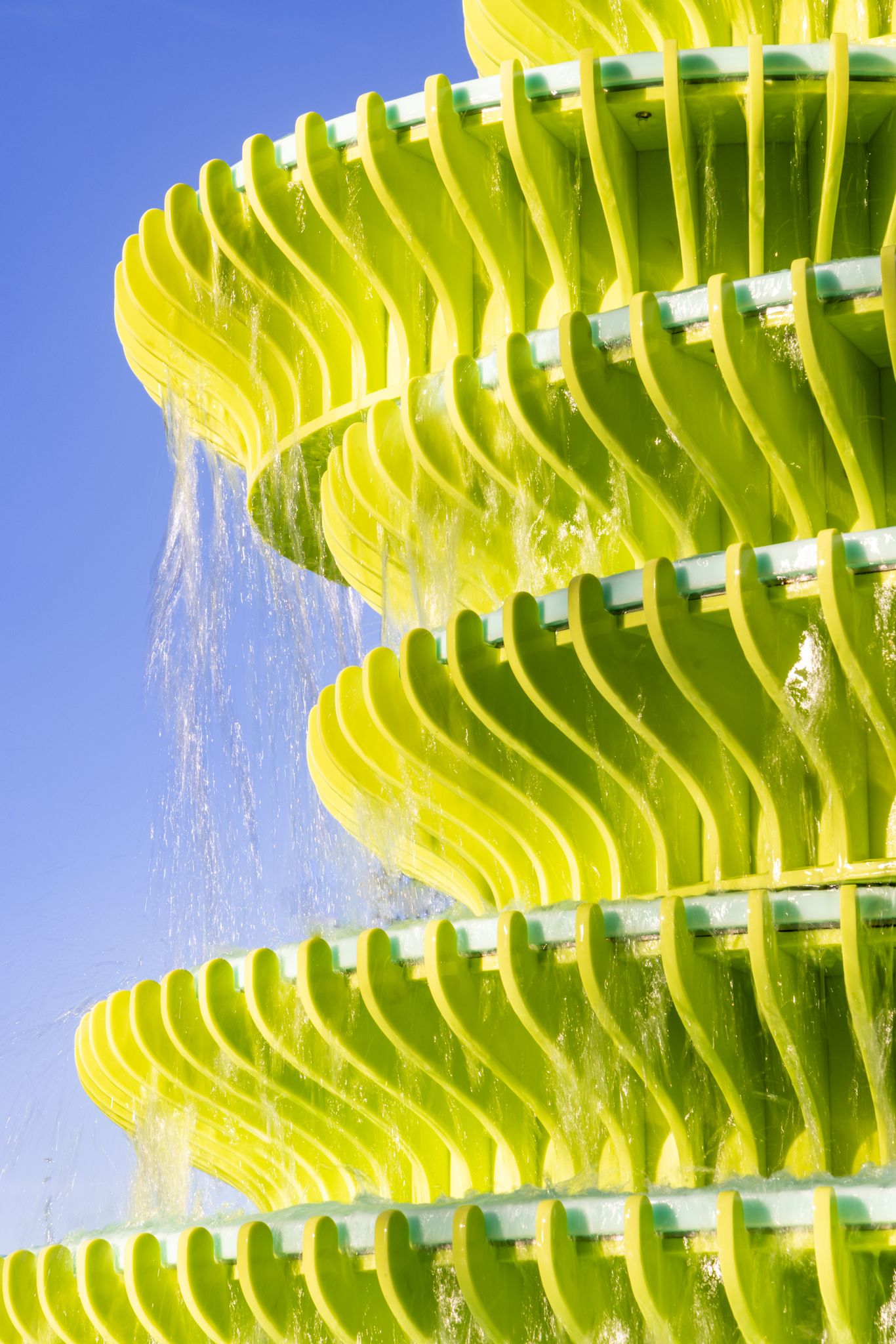 Water falling over the green fins of the fountain