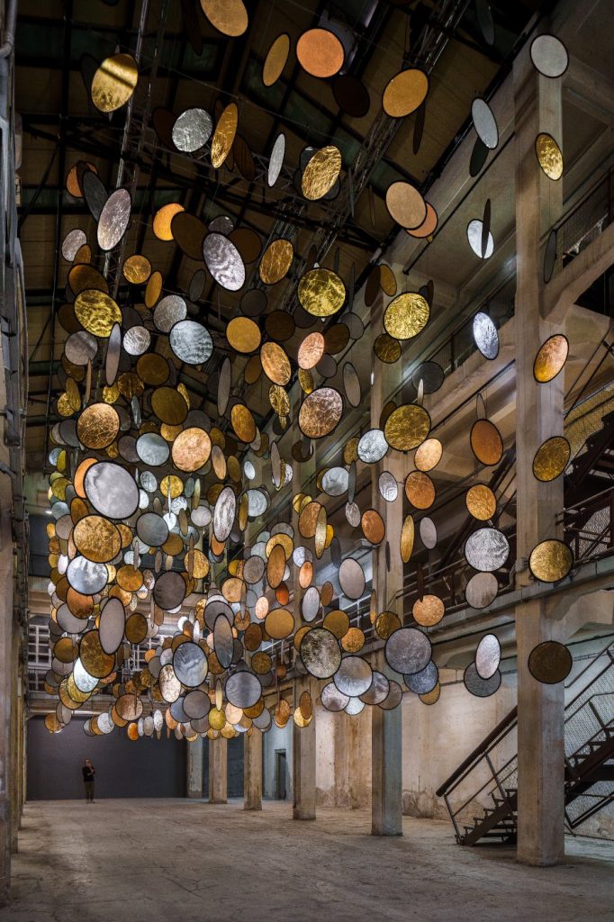 SpY, HALOS, gold and silver reflective circles suspended in a former railway factory in Florence