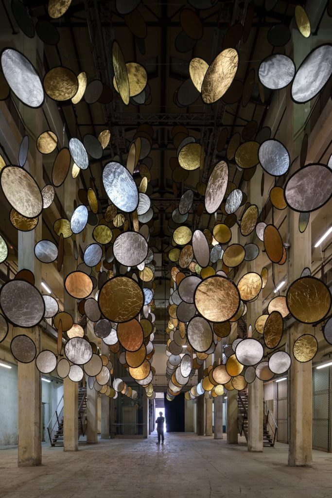 SpY, HALOS, gold and silver reflective circles suspended in a former railway factory in Florence