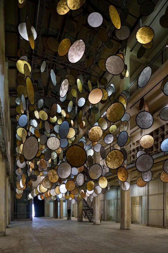 SpY, HALOS, gold and silver reflective circles suspended in a former railway factory in Florence