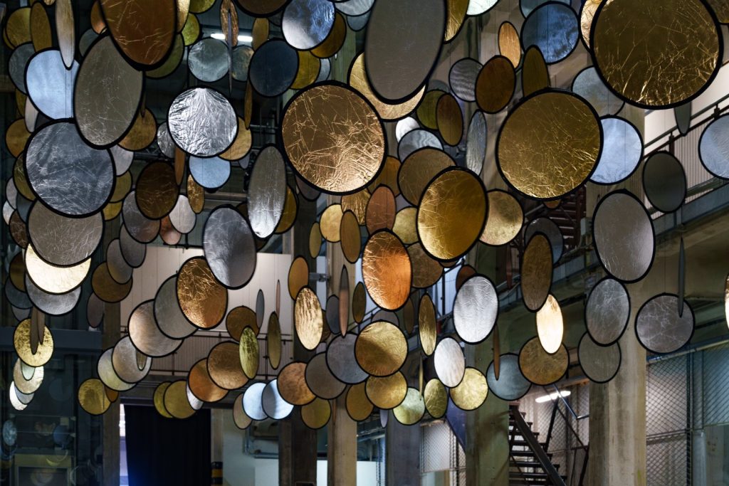 SpY, HALOS, gold and silver reflective circles suspended in a former railway factory in Florence