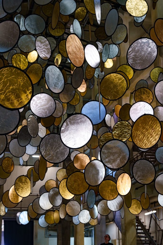 SpY, HALOS, gold and silver reflective circles suspended in a former railway factory in Florence