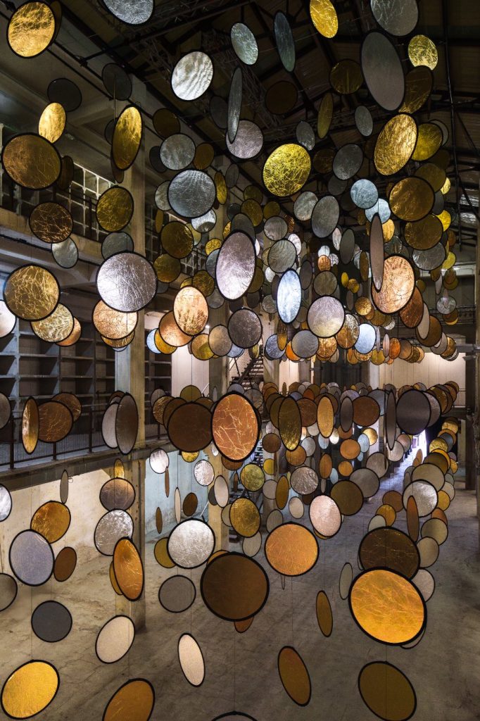 SpY, HALOS, gold and silver reflective circles suspended in a former railway factory in Florence