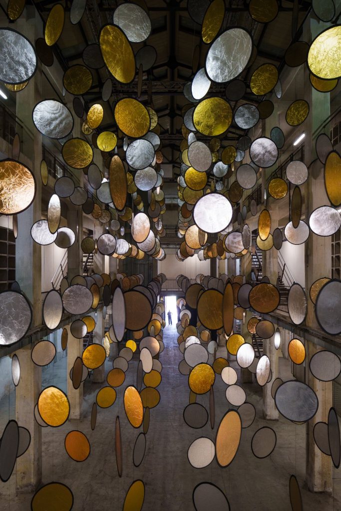SpY, HALOS, gold and silver reflective circles suspended in a former railway factory in Florence