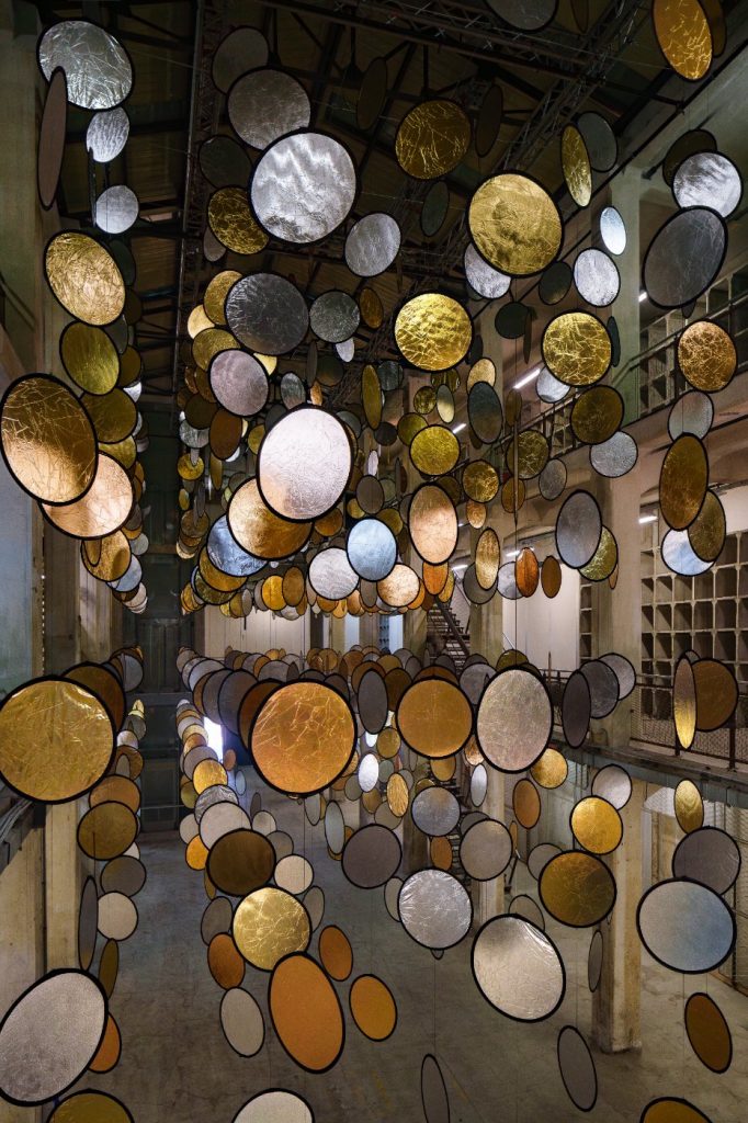 SpY, HALOS, gold and silver reflective circles suspended in a former railway factory in Florence