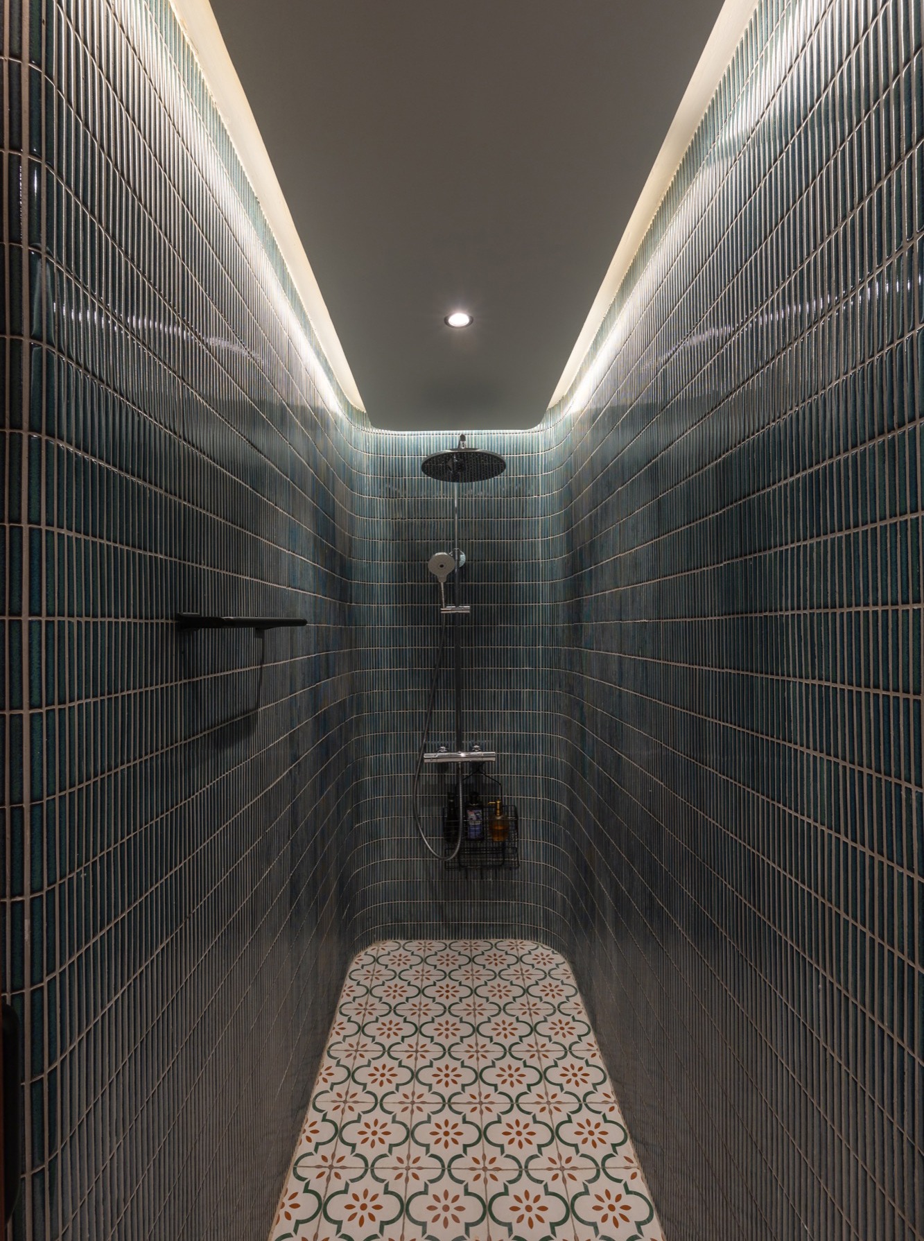 The shower room, lined in dark green tiles with a cement tile floor