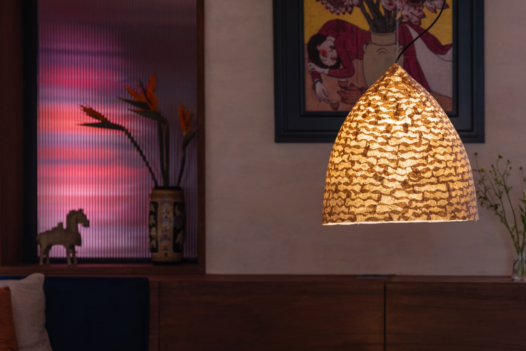 A woven lamp beside a painting